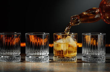 Whiskey is poured into a glass with ice.