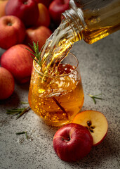 Apple juice is poured from a bottle into a glass.