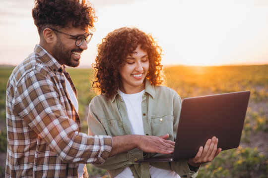 Agronomists using laptop in soybean field at sunset - Powered by Adobe