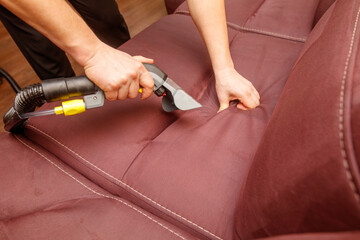 A person is cleaning a couch with a vacuum