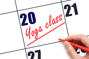 20th day of the month.  Hand writing Yoga class reminder and drawing a line on calendar with red pen on white background. Concept of sport and fitness activity.  Planning and scheduling
