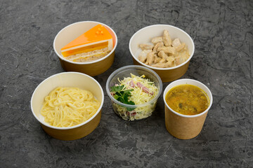 mega lunch soup, meat stewed in sauce and vermicelli with cheese with coleslaw in disposable dishes on a gray background