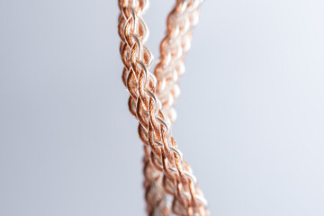 Macro shot of vertically hanging braided copper and silver cable used for high-end audio setups.
