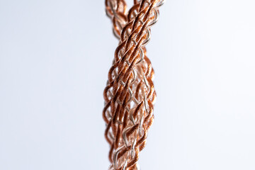 Macro shot of vertically hanging braided copper and silver cable used for high-end audio setups.