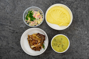 lunch soup, mashed potatoes and cutlet with onion and salad in disposable dishes