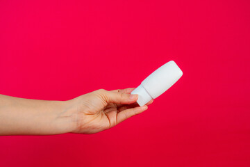 Skin care or sunscreen cosmetic and hand on red background.