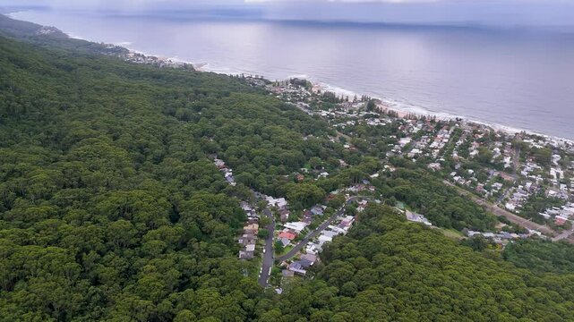 South Coast, NSW, Australia: High-flying drone sweeping the coastline between Sydney and Wollongong with magnificent panoramic views, gorgeous beaches and a string of rainy clouds over the ocean.