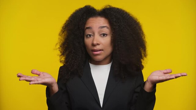 Confused Woman Shrugging Shoulders on Yellow Background