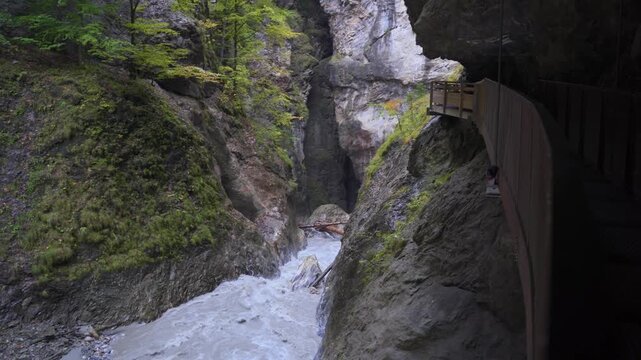 Path along a gorge. Rocky steep gorge with trees and a river winding through it.