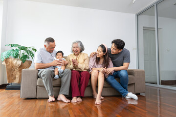 Joyful Grandparents, Parents, and Baby Bonding Together, Three Generations of Asian Family Relaxing and Smiling, Happy Multi-Generational Asian Family on Sofa at Home
