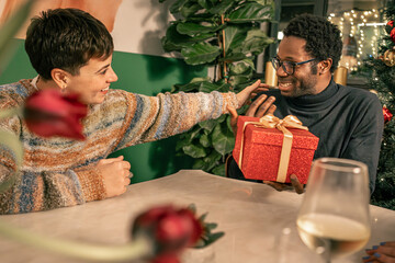 Happy diverse couple talking and celebrating at a Christmas party. A non-binary person and a Black...