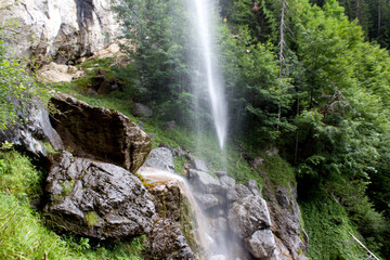 Experiencing the serene beauty of Schleierwasserfall in Tyrol, Austria during a refreshing summer day, surrounded by lush greenery and natural rock formations