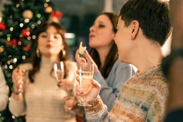 A joyful group of diverse friends laughing and toasting at a Christmas party. Multi-ethnic people sharing a happy moment with sparkling wine during a festive holiday gathering.