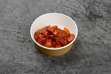 fried meat in tomato sauce in a disposable container