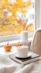 Fototapeta premium White mug with hot chocolate, marshmallows, pumpkins, books blanket fall by the window during a cozy and season