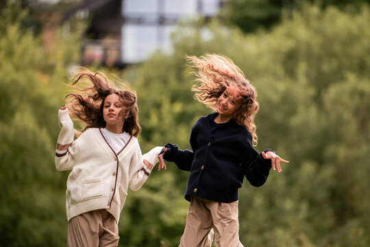 Two young girls, sisters, running together with happy faces