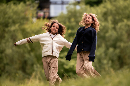 Two young girls, sisters, running together with happy faces