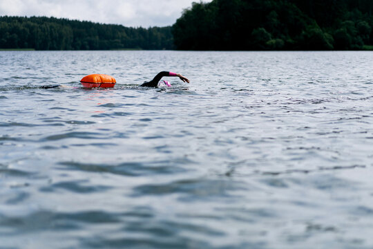 Woman in wetsuit with buoy swimming across lake, open water training