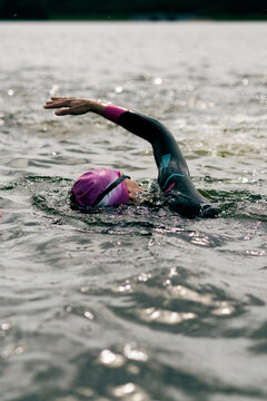 Woman in wetsuit with buoy swimming across lake, open water training