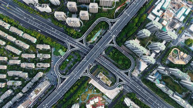 Aerial top down view of a complex junction with multiple lanes and green spaces in a bustling urban area. Hangzhou, China.