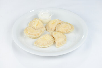 boiled dumplings with sour cream on a white plate