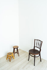 Wooden chairs of different sizes arranged in a white corner