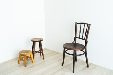 Wooden chairs of different sizes arranged in a white corner