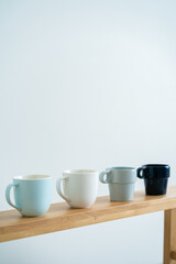 Minimalist cups on a wooden bench against white wall