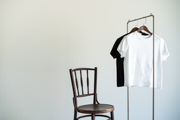 Minimal clothing setup with wooden chair and monochrome T-shirts