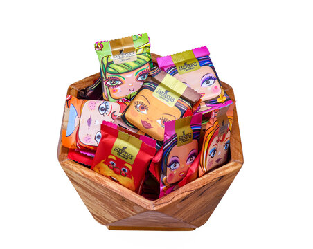 Germany Berlin july24,2025, A wooden bowl filled with colorful merdas candy packages featuring illustrated cartoon faces on glossy wrappers. The variety of characters and vivid colors create a playful