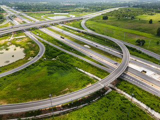 Drone shot a large highway interchange crossing over green farmlands in Thailand