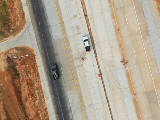 Aerial view of new road construction with vehicles on partially completed highway section