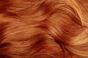 Red hair close-up as a background. Women's long orange hair. Beautifully styled wavy shiny curls....