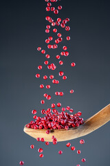 Aromatic dried spice berries fall from above onto a wooden spoon, ideal for gourmet cooking and...