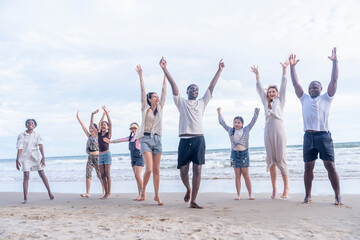 group of diverse friends and family gathering on the beach doing hands up together in the evening...