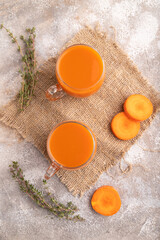 Two glasses with carrot juice, on brown concrete background and linen textile. Diet, healthy eating. top view, close up