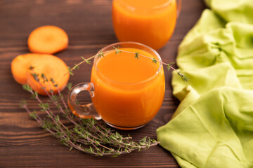 Two glasses with carrot juice, on wooden background and green textile. Diet, healthy eating. side view, selective focus