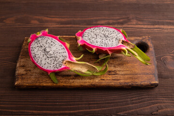 Ripe Pitaya on cutting board on brown wooden background, side view, copy space