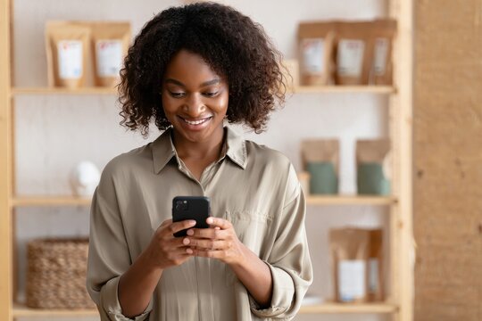 Smiling african american woman using smartphone for online shopping and social media