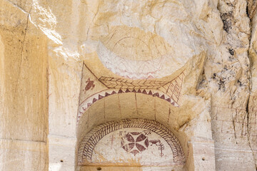 Primitive red-ochre Byzantine fresco in rock-carved arch at medieval monastery in Goreme Open Air Museum, Cappadocia, Turkey