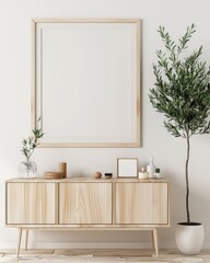 A wooden console table with a large empty picture frame. a vase of flowers. and a plant in a white pot The table is sitting in front of a white wall
