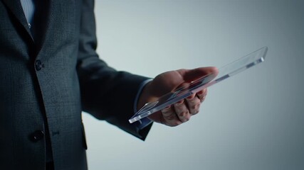 Hand Holding Transparent Digital Tablet Wearing Dark Business Suit Against Soft Grey Background in a Corporate Setting - Powered by Adobe