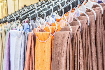 Neatly arranged earth-toned fabrics on hangers at a textile street shop in Turkey
