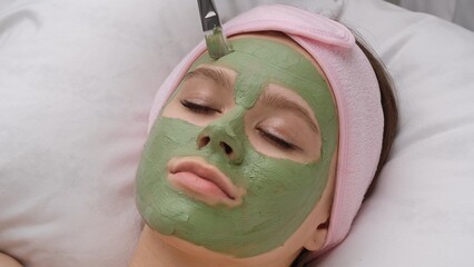 Woman Relaxing with Rejuvenating Green Facial Mask Treatment