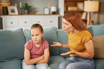 A mother is having a serious discussion with her daughter who appears upset. They sit on a...