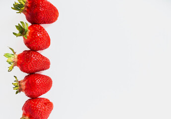 a row of red strawberries on a white background with a space for copying