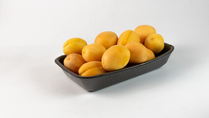 a tray with apricots on a white background