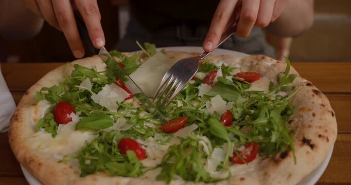 Savoring a fresh, artisanal pizza topped with greens, tomatoes, and cheese at a quaint eatery during a sunny afternoon