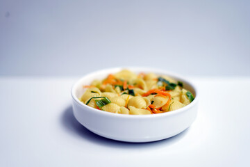 Tasty Mixed Vegetable Pasta in White Ceramic Bowl on White Table