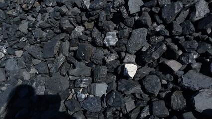 A close-up of dark gray gravel and small stones scattered across a rough, uneven surface, with subtle texture and natural lighting highlighting the granular details